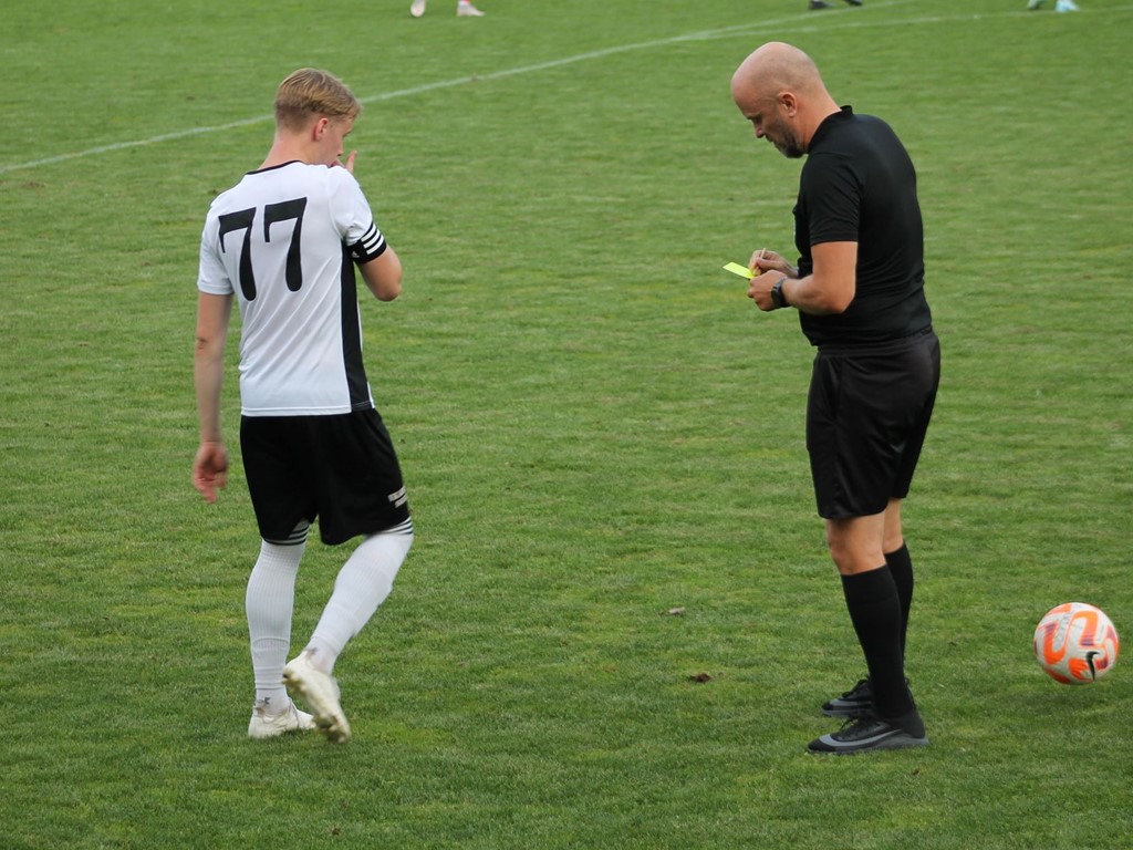 Duktige matchledaren Roger Lundbäck i varningstagen. Östavalls lagkapten Martin Edlund noterar. Foto: Roger Mattsson, Lokalfotbollen.nu,
